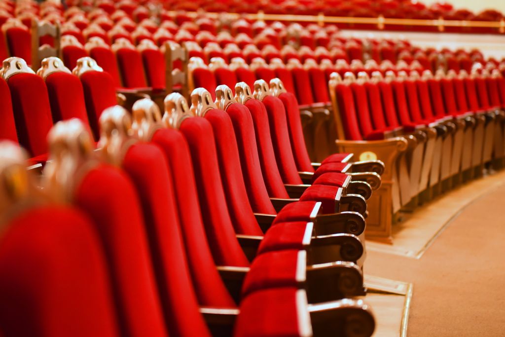 Rows of elegant red seats in a beautifully empty theater auditorium capture a sense of anticipation.
